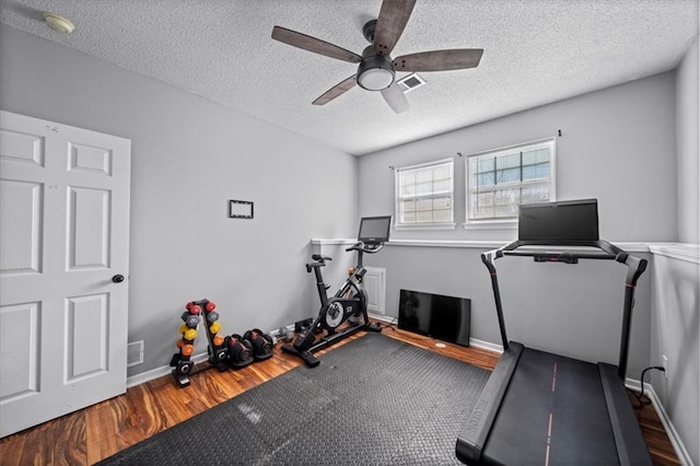 workout area with a textured ceiling, wood finished floors, and visible vents