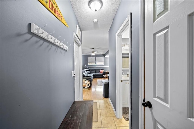 hall featuring light tile patterned floors and a textured ceiling