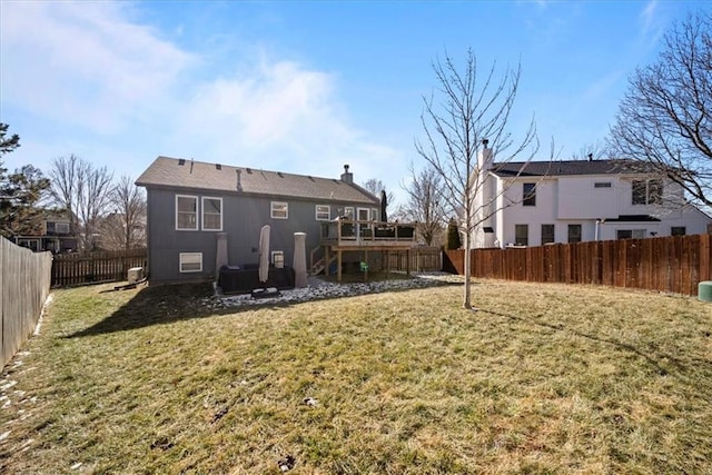 rear view of property with a fenced backyard, a deck, and a yard