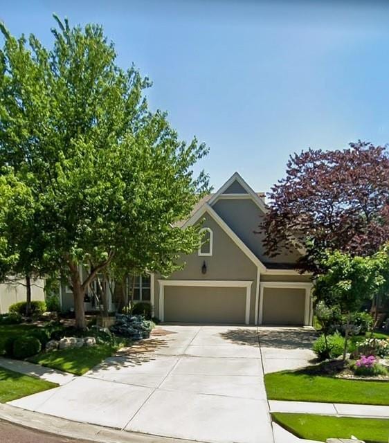 obstructed view of property featuring a garage, driveway, and stucco siding