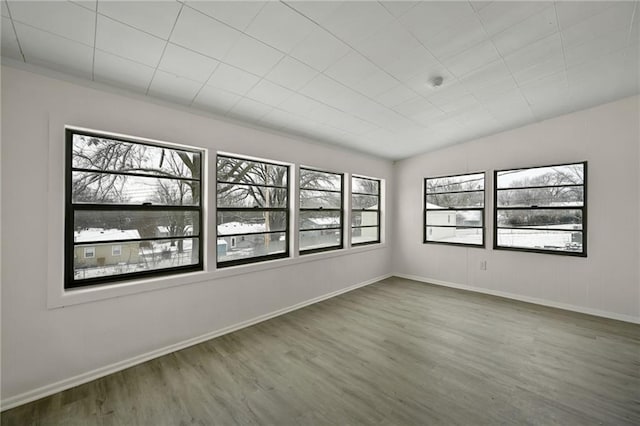 empty room featuring plenty of natural light, wood finished floors, and baseboards