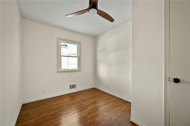 unfurnished room featuring visible vents, dark wood finished floors, and ceiling fan