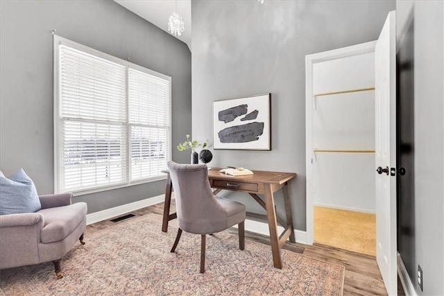 office with light hardwood / wood-style floors and a chandelier