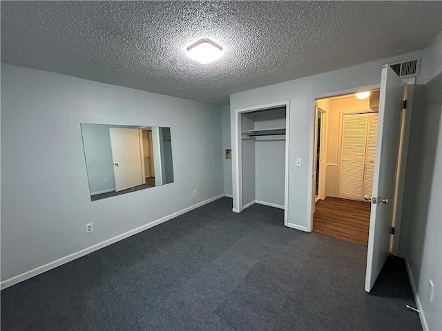 unfurnished bedroom featuring dark carpet, a textured ceiling, and a closet