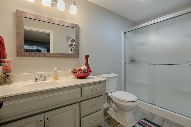 bathroom with hardwood / wood-style flooring, an enclosed shower, vanity, and toilet