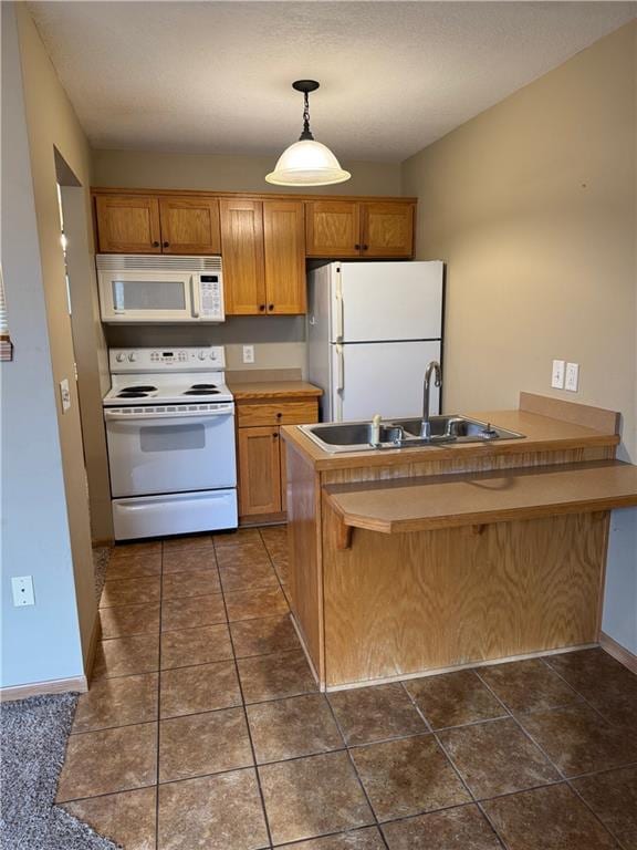 kitchen with kitchen peninsula, decorative light fixtures, sink, white appliances, and a breakfast bar area