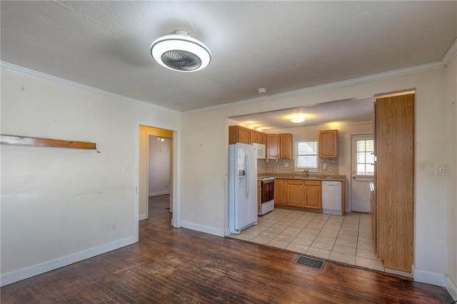 kitchen with visible vents, backsplash, a sink, light wood-type flooring, and white appliances