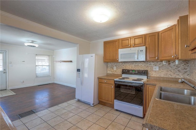 kitchen with white appliances, tasteful backsplash, light tile patterned floors, visible vents, and a sink