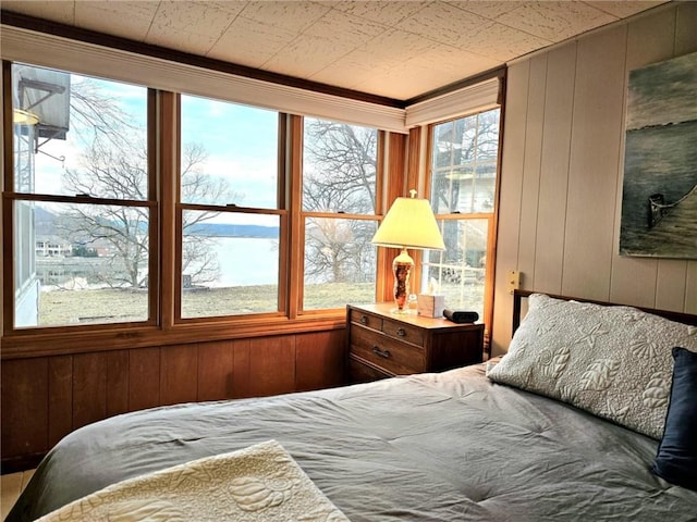 bedroom with a water view, wood walls, and multiple windows