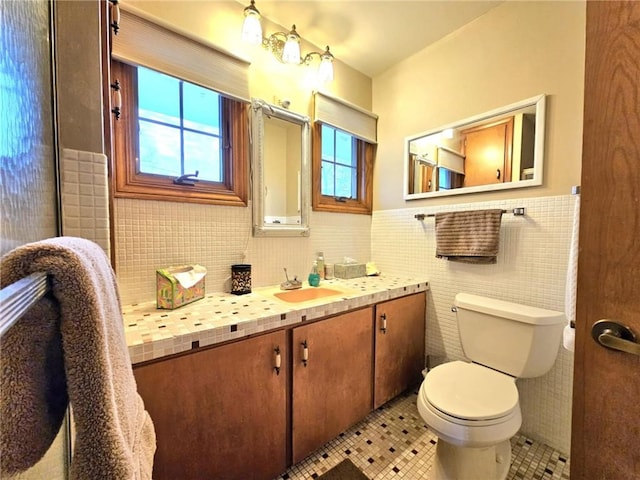 bathroom with wainscoting, toilet, tile patterned floors, vanity, and tile walls