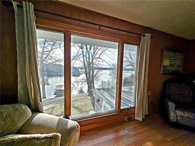 entryway featuring a water view, plenty of natural light, wood walls, and wood finished floors