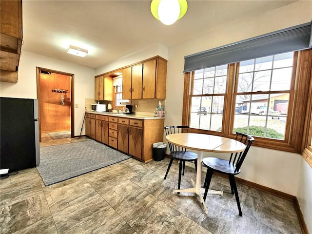 kitchen with brown cabinetry, light countertops, and baseboards