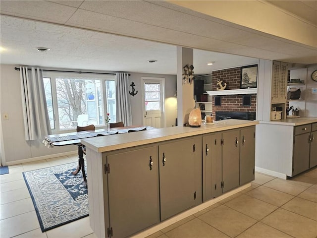 kitchen with light tile patterned floors, light countertops, baseboards, and a center island