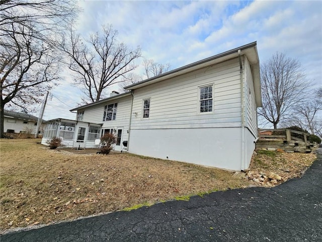 back of house featuring a lawn and a sunroom