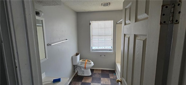 bathroom with a washtub, a shower, toilet, a textured ceiling, and baseboards