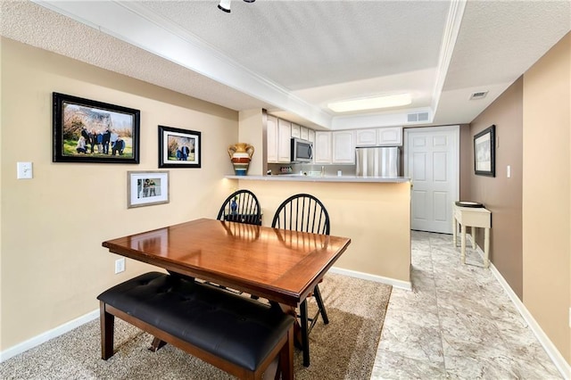 dining area featuring a raised ceiling, baseboards, visible vents, and a textured ceiling