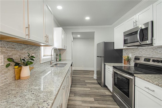 kitchen featuring dark wood finished floors, appliances with stainless steel finishes, ornamental molding, white cabinets, and a sink