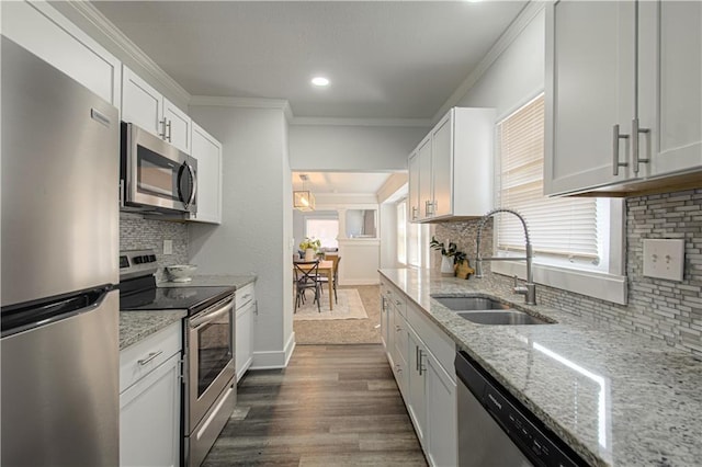 kitchen featuring white cabinets, ornamental molding, dark wood-type flooring, stainless steel appliances, and a sink