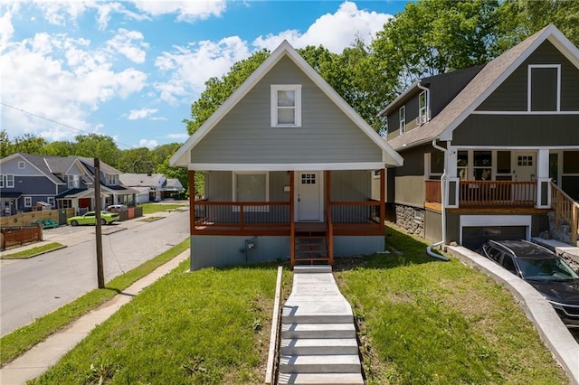 view of front of property with a front lawn, a porch, stairway, a residential view, and a garage