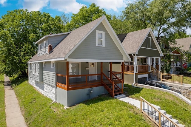 3946 Flora Ave, Kansas City, MO 64110 - view of front of home with a front yard, covered porch, stairway, and roof with shingles