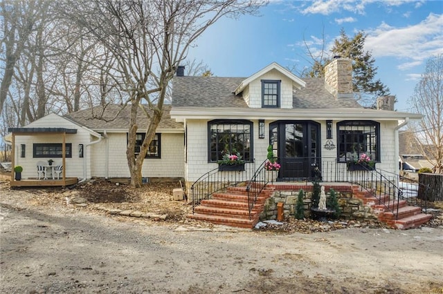 view of front of home with covered porch, a shingled roof, and a chimney