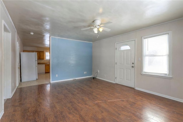 foyer entrance featuring wood finished floors, ornamental molding, baseboards, and a ceiling fan