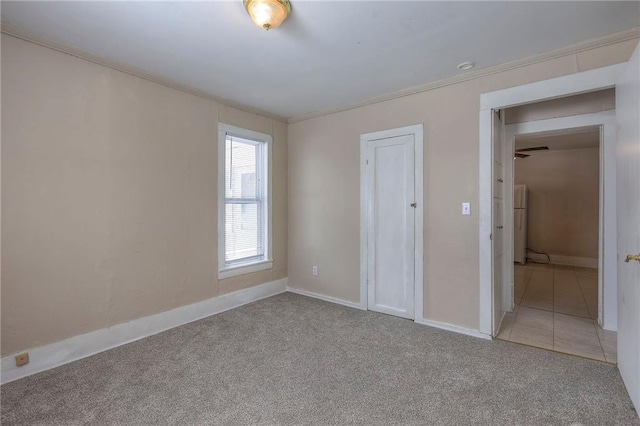unfurnished bedroom with ornamental molding, baseboards, and light carpet