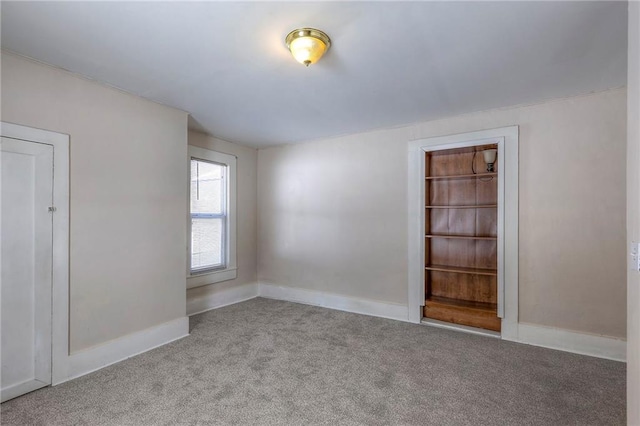 carpeted spare room featuring baseboards