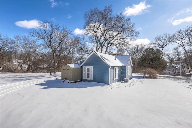 snow covered property with a shed and an outdoor structure