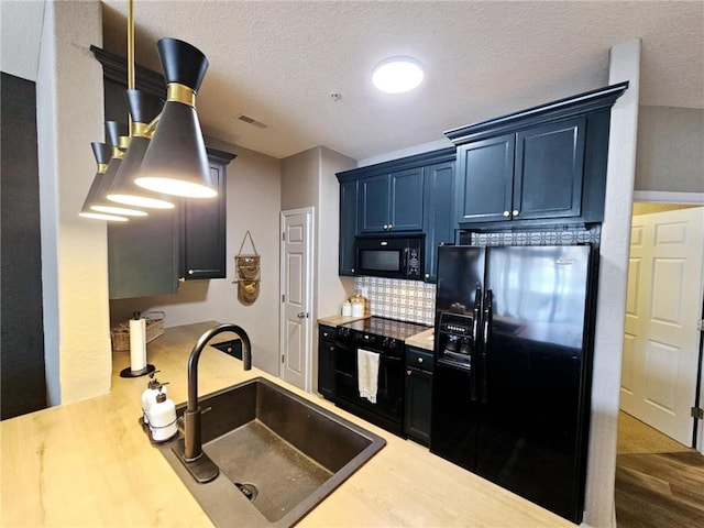 kitchen featuring a sink, visible vents, light countertops, black appliances, and tasteful backsplash