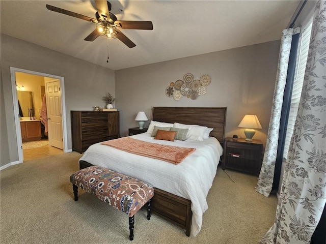 bedroom with baseboards, light carpet, ceiling fan, and ensuite bath