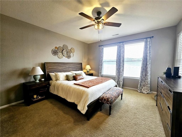 carpeted bedroom featuring a ceiling fan, visible vents, baseboards, and a textured ceiling