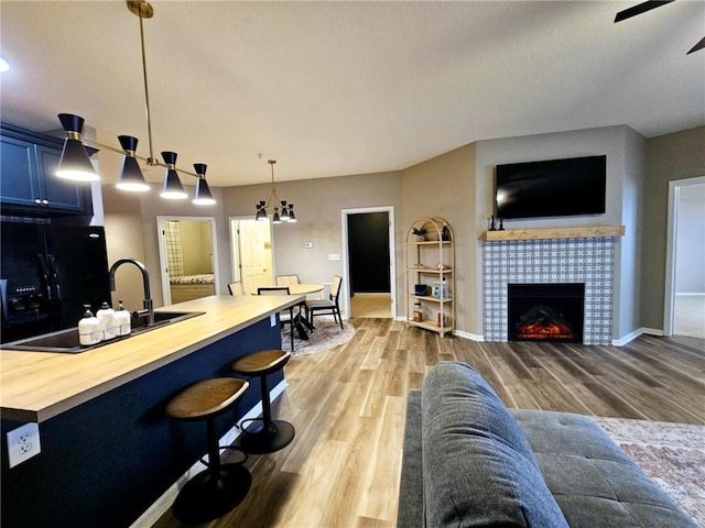 living area featuring light wood finished floors, baseboards, a ceiling fan, and a tile fireplace