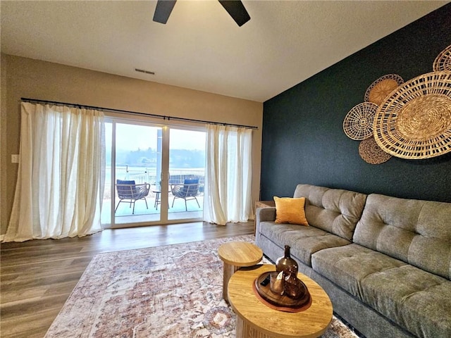 living area with vaulted ceiling, a water view, ceiling fan, and wood finished floors