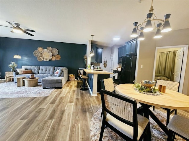 dining space with ceiling fan, an accent wall, and light wood finished floors