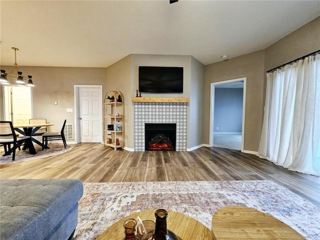 living room with a fireplace, baseboards, and wood finished floors