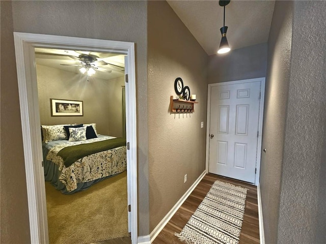 doorway to outside with a ceiling fan, dark wood-style flooring, a textured wall, and baseboards