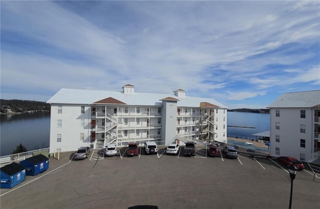 view of building exterior featuring uncovered parking and a water view