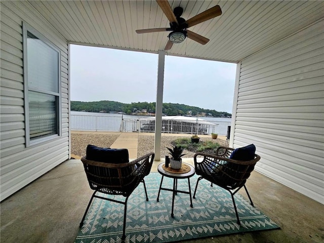 view of patio with a water view, ceiling fan, and fence