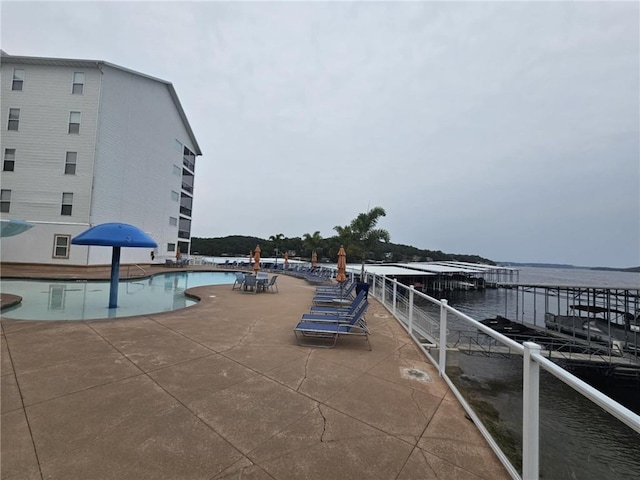 view of pool featuring a water view and a patio