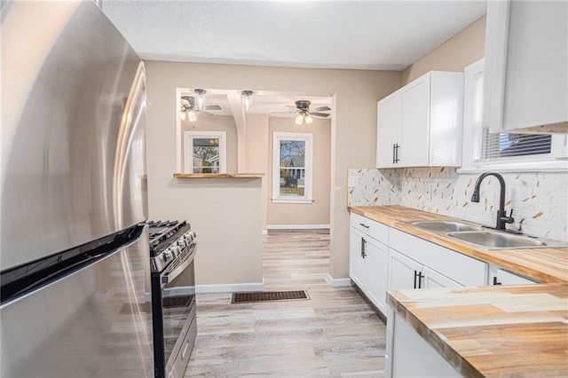 kitchen featuring appliances with stainless steel finishes, sink, butcher block countertops, and white cabinetry