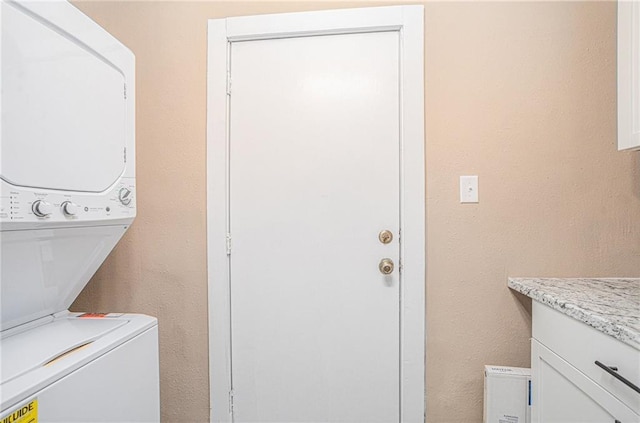 clothes washing area featuring cabinets and stacked washer and dryer