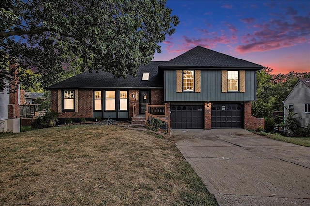 tri-level home featuring driveway, an attached garage, a front yard, and brick siding