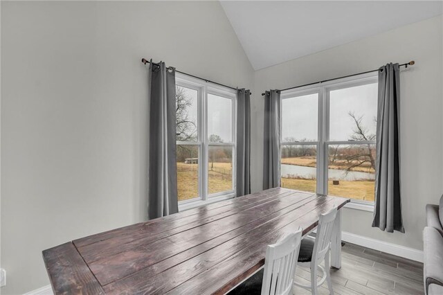 dining room featuring lofted ceiling, baseboards, and wood finished floors