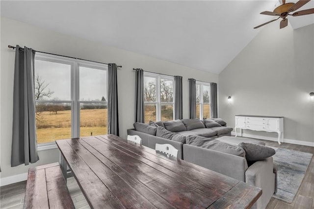 living room featuring high vaulted ceiling, ceiling fan, baseboards, and wood finished floors