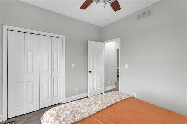 bedroom with a closet, visible vents, a ceiling fan, wood finished floors, and baseboards