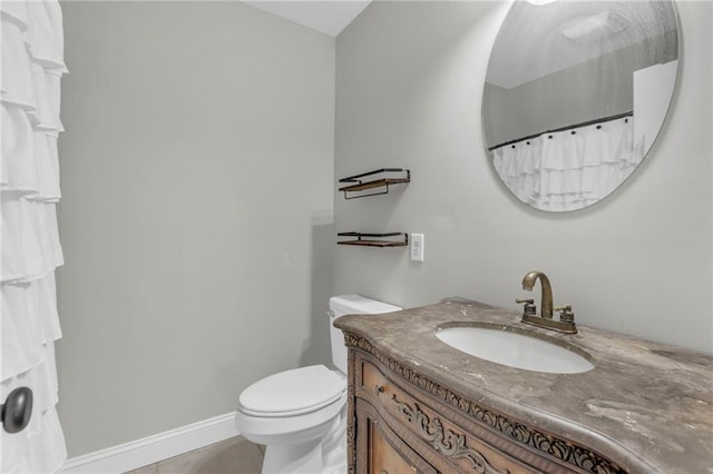 bathroom featuring baseboards, vanity, and toilet