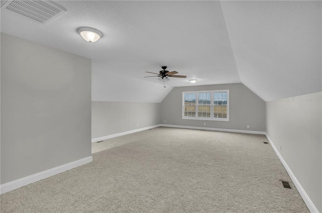 additional living space with baseboards, visible vents, vaulted ceiling, and carpet flooring