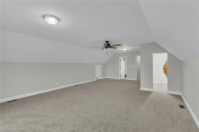 additional living space with visible vents, baseboards, ceiling fan, carpet, and vaulted ceiling