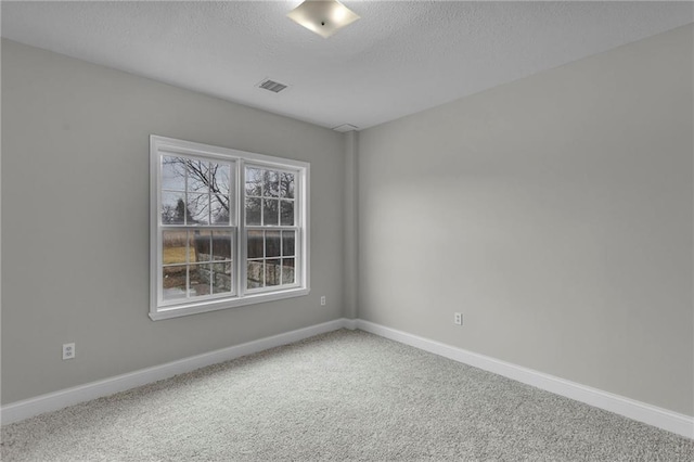 empty room featuring a textured ceiling, carpet flooring, and baseboards